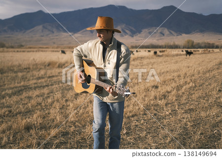 A shepherd is dancing in a field with a guitar in his hands. A man in a cowboy hat is playing guitar in a field. A musician is tending a herd of cows with a guitar in his hands A shepherd is dancing in a field with a guitar in his hands. A man in a cowboy hat is playing guitar in a field. A musician is tending a herd of cows with a guitar in his hands 138149694