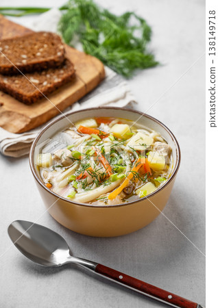 Chicken noodle soup with fresh dill in a yellow bowl on a light textured background Chicken noodle soup with fresh dill in a yellow bowl on a light textured background 138149718