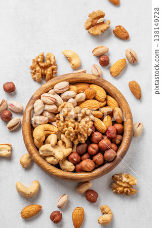 A mix of almonds, cashews, hazelnuts, walnuts, and pistachios in a wooden bowl on a light background 138149728