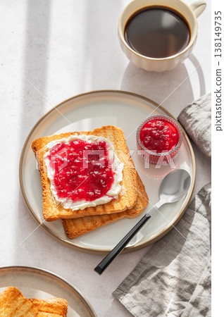 Toast with sweet berry-fruit jam and cream cheese on a plate on a light concrete background Toast with sweet berry-fruit jam and cream cheese on a plate on a light concrete background 138149735