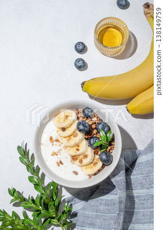 Natural greek yogurt with granola, blueberry and banana in a bowl on a light concrete background Natural greek yogurt with granola, blueberry and banana in a bowl on a light concrete background 138149759