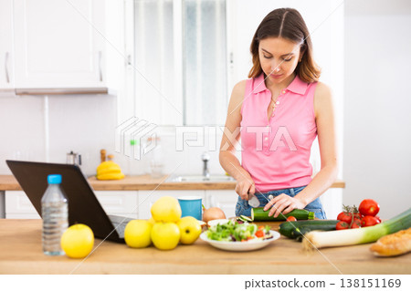 Woman cooking salad recipe from the Internet Woman cooking salad recipe from the Internet 138151169