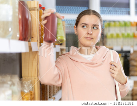 Female shopper chooses bottle of smoothie while shopping in supermarket Female shopper chooses bottle of smoothie while shopping in supermarket 138151191
