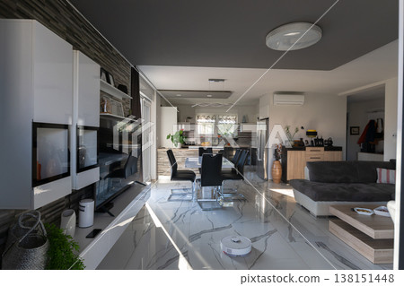 Modular house interior with smart vacuum at sunset in modern open-plan living and dining space Modular house interior with smart vacuum at sunset in modern open-plan living and dining space 138151448