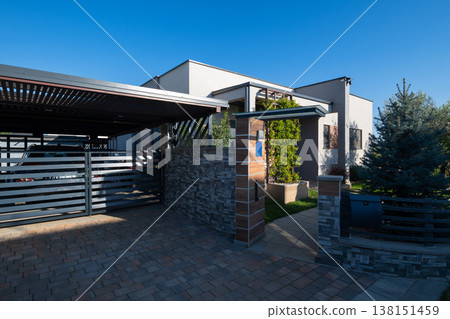 Modern modular house exterior with carport, gated driveway and smart home features at sunset Modern modular house exterior with carport, gated driveway and smart home features at sunset 138151459