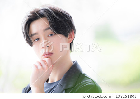 Close-ups of young male employees and men looking directly at the camera in thoughtful poses by a window surrounded by fresh greenery, reflecting their struggles with their careers. Close-ups of young male employees and men looking directly at the camera in thoughtful poses by a window surrounded by fresh greenery, reflecting their struggles with their careers. 138151805