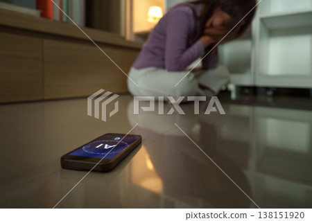 Woman sitting on the floor with a phone nearby Woman sitting on the floor with a phone nearby 138151920