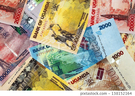 Ugandan shilling paper banknotes pile on table. Uganda UGX currency money bills in big amount. Concept of economics, taxation and banking in Uganda Ugandan shilling paper banknotes pile on table. Uganda UGX currency money bills in big amount. Concept of economics, taxation and banking in Uganda 138152164