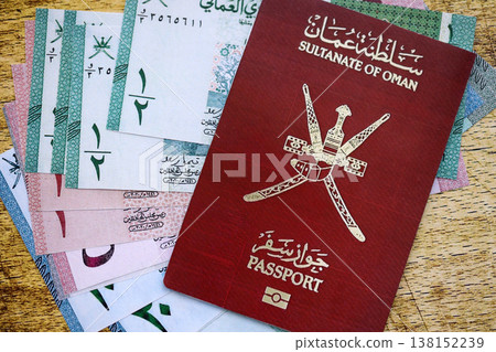 Omani passport on table and money. Official identification document book for citizens of Oman. Concept of travel and tourism 138152239