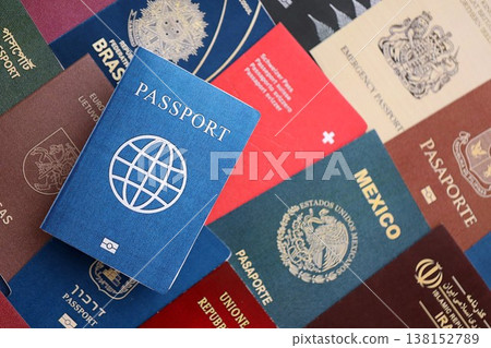 Fictional passport book travel document on big amount of real passport covers of various different countries. Expired passports in big pile close up. Travel documents for tourism Fictional passport book travel document on big amount of real passport covers of various different countries. Expired passports in big pile close up. Travel documents for tourism 138152789