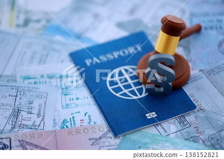 Paragraph symbol and judge hammer on passport pages full of colorful stamps after travel and tourism. Border control and lawsuit concept. Immigration and travel around the world 138152821
