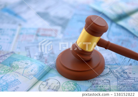Judgement gavel on passport pages full of colorful stamps after travel and tourism. Border control and lawsuit concept. Immigration and travel around the world Judgement gavel on passport pages full of colorful stamps after travel and tourism. Border control and lawsuit concept. Immigration and travel around the world 138152822