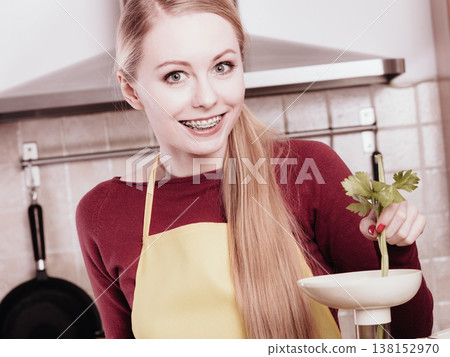 Woman in kitchen making vegetable smoothie juice 138152970