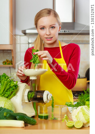 Woman in kitchen making vegetable smoothie juice 138152971