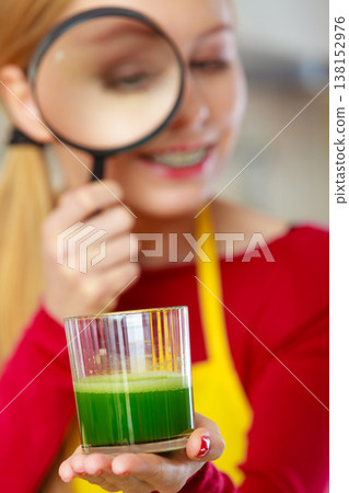Woman looking at vegetable juice through magnifying glass 138152976