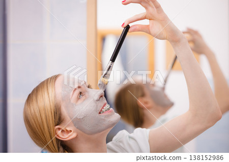 Woman applying with brush clay mud mask to her face Woman applying with brush clay mud mask to her face 138152986