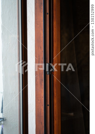 Wooden window or door frame showing security lock, a detail of modern interior architecture and home design focusing on a closed brown wood door Wooden window or door frame showing security lock, a detail of modern interior architecture and home design focusing on a closed brown wood door 138152999