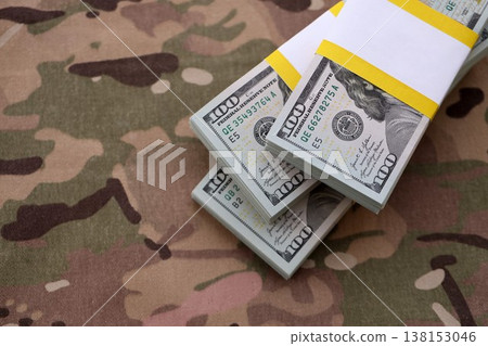 Three packs of ten thousand US dollar bills on camouflage background. Packs of hundred dollar bills in stack on army fabric close up 138153046