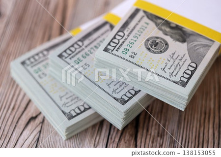 Three packs of ten thousand US dollar bills on wooden background. Packs of hundred dollar bills in stack on brown wood planks close up Three packs of ten thousand US dollar bills on wooden background. Packs of hundred dollar bills in stack on brown wood planks close up 138153055