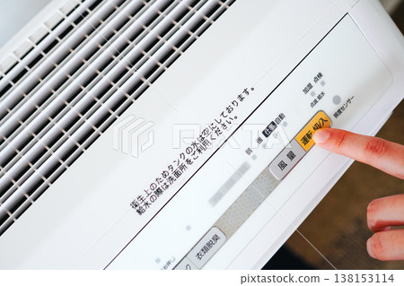A woman's hands are shown turning on a dehumidifier with a clothes deodorizing function, and the control panel of the appliance. 138153114