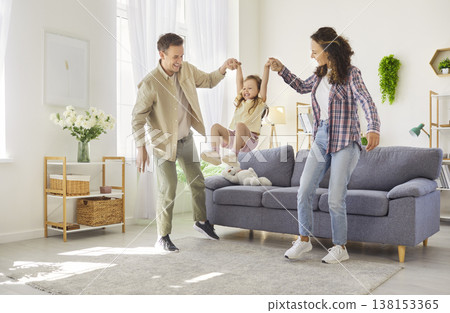 Happy parents swing their laughing daughter while playing together at home Happy parents swing their laughing daughter while playing together at home 138153365