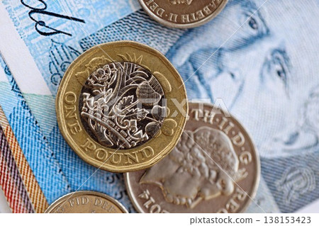British pound money bills and penny coins pile on table. United Kingdom coins on banknotes of GBP currency close up. Concept of business, taxes and banking in United Kingdom 138153423