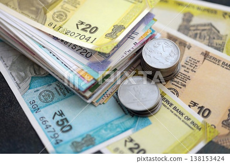 Indian rupee money bills and paisa coins pile on table. India coins on banknotes of INR currency close up. Concept of business, taxes and banking in India Indian rupee money bills and paisa coins pile on table. India coins on banknotes of INR currency close up. Concept of business, taxes and banking in India 138153424