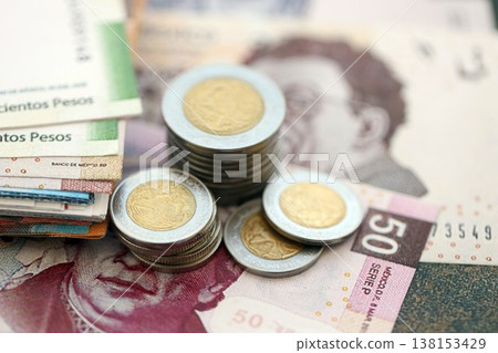 Mexican peso money bills and centavo coins pile on table. Mexico coins on banknotes of MXN currency close up. Concept of business, taxes and banking in Mexico 138153429