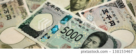 Japanese yen money bills pile on table. Japan banknotes of JPY currency close up. Concept of business, economy and banking in Japan Japanese yen money bills pile on table. Japan banknotes of JPY currency close up. Concept of business, economy and banking in Japan 138153467