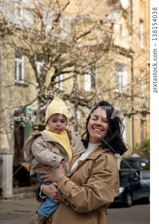 Mother holding toddler on city street in spring 138154038
