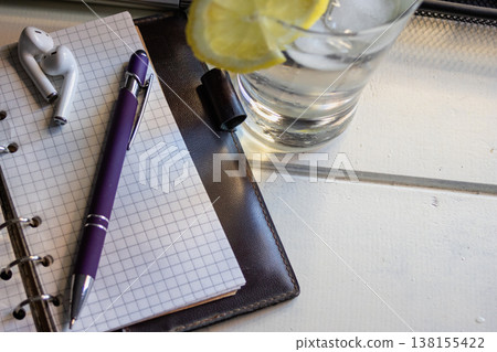 Home office remote working setup next to a refreshing glass of water with lemon on a white wooden table 138155422