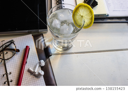 Remote worker productivity concept featuring a casual work environment with essential tools and a refreshing drink Remote worker productivity concept featuring a casual work environment with essential tools and a refreshing drink 138155423