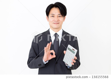 一位中年商人手持計算器,做了一個畫圈的手勢。 一位中年商人手持計算器,做了一個畫圈的手勢。 138155568