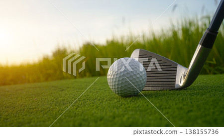 Golf clubs and balls on a green lawn in a beautiful golf course with morning sunshine. Golf clubs and balls on a green lawn in a beautiful golf course with morning sunshine. 138155736