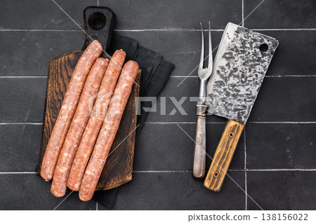 Raw fresh sausages on wooden board over dark slate background. Uncooked pork meat links with spices and fat texture. Butcher ingredient with copy space. Raw fresh sausages on wooden board over dark slate background. Uncooked pork meat links with spices and fat texture. Butcher ingredient with copy space. 138156022