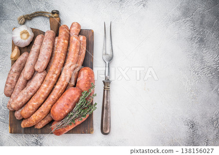 Raw sausage assortment on wooden board isolated on white background. Fresh seasoned pork meat links perfect for grilling barbecue cooking. Raw sausage assortment on wooden board isolated on white background. Fresh seasoned pork meat links perfect for grilling barbecue cooking. 138156027