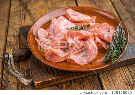 Sliced salami sausage served on ceramic plate with herbs on rustic wooden table. Italian cured pork charcuterie with copy space. Sliced salami sausage served on ceramic plate with herbs on rustic wooden table. Italian cured pork charcuterie with copy space. 138156050