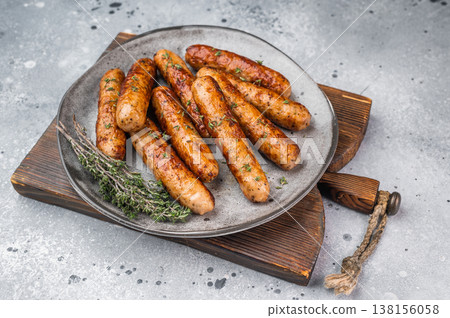 Cooked grilled sausages with thyme seasoning on plate over gray stone background. Juicy pork meat links ready to serve. 138156058