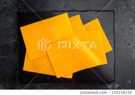 Stack of orange cheese slices on black stone background minimal food composition with copy space for menu or design 138156150