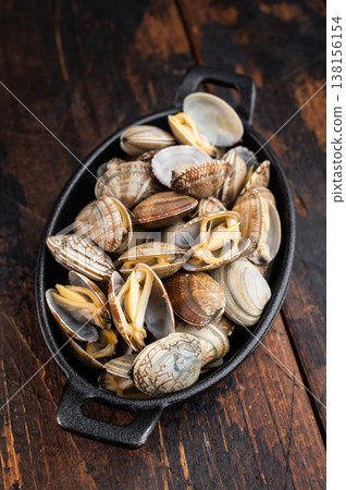 Steamed vongole mollusks in black cast iron skillet. Mediterranean seafood composition with shells, rosemary and salt. 138156154