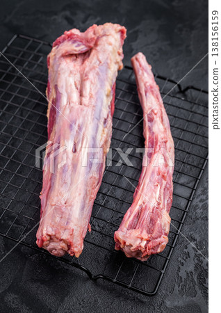Raw beef oxtail segments on metal rack over dark textured background with copy space, butcher meat for broth and slow cooking Raw beef oxtail segments on metal rack over dark textured background with copy space, butcher meat for broth and slow cooking 138156159