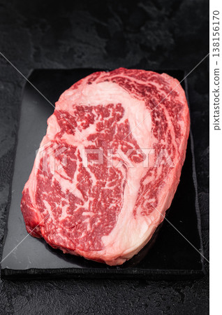 Fresh raw ribeye beef steak, marbled rib fillet cut, premium red meat for grilling roasting or steakhouse cooking on dark background Fresh raw ribeye beef steak, marbled rib fillet cut, premium red meat for grilling roasting or steakhouse cooking on dark background 138156170