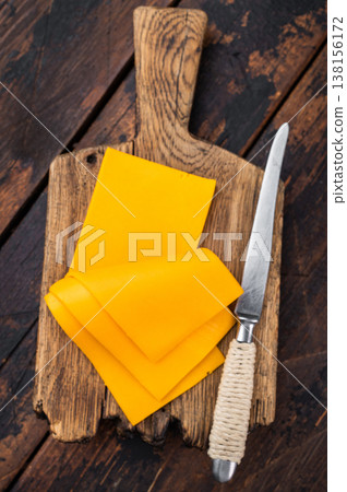Stack of orange cheese slices on board with knife dark wooden background dairy ingredient for sandwiches burgers and cooking Stack of orange cheese slices on board with knife dark wooden background dairy ingredient for sandwiches burgers and cooking 138156172
