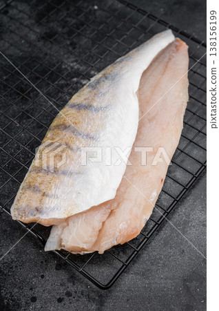 Raw pike perch fillets on dark background, one skin-on and one skinless, fresh freshwater white fish meat ready for cooking. Raw pike perch fillets on dark background, one skin-on and one skinless, fresh freshwater white fish meat ready for cooking. 138156199