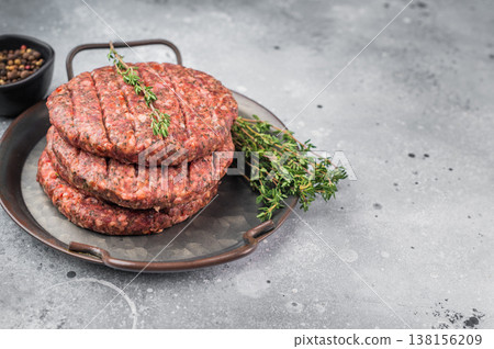 Raw Uncooked beef lamb minced meat patty with herbs and pepper in pan. Overhead view on light stone background with copy space. 138156209
