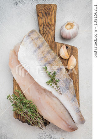 Raw pike perch fillets on light background with garlic and thyme, fresh lean freshwater white fish ready for cooking. Raw pike perch fillets on light background with garlic and thyme, fresh lean freshwater white fish ready for cooking. 138156211