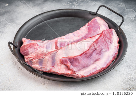 Fresh raw lamb meat ribs and breast with herbs and garlic in skillet on light stone background uncooked ingredient for roasting and bbq Fresh raw lamb meat ribs and breast with herbs and garlic in skillet on light stone background uncooked ingredient for roasting and bbq 138156220