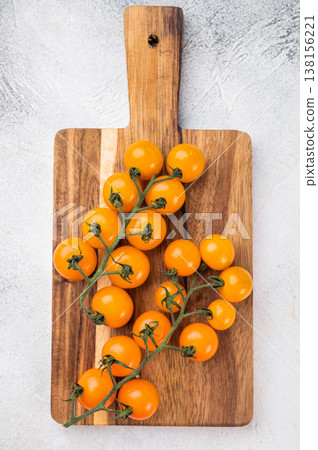 Ripe cherry tomato cluster on rustic wooden board, top view on bright stone surface, natural vegetarian food ingredient 138156221