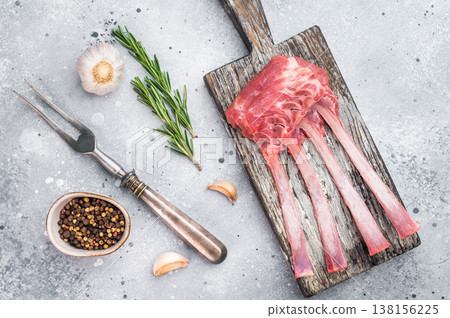 Uncooked lamb ribs and cutlets with herbs and spices on wooden board stone background top view butcher preparation Uncooked lamb ribs and cutlets with herbs and spices on wooden board stone background top view butcher preparation 138156225