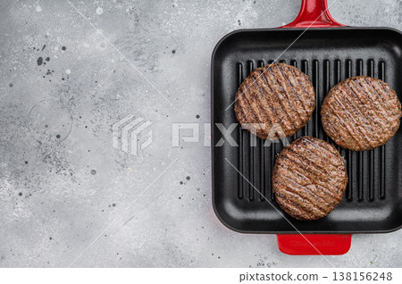 Grilled beef and lamb burger patties with seared crust in cast iron grill pan. Cooked juicy meat on light stone background with copy space. Grilled beef and lamb burger patties with seared crust in cast iron grill pan. Cooked juicy meat on light stone background with copy space. 138156248